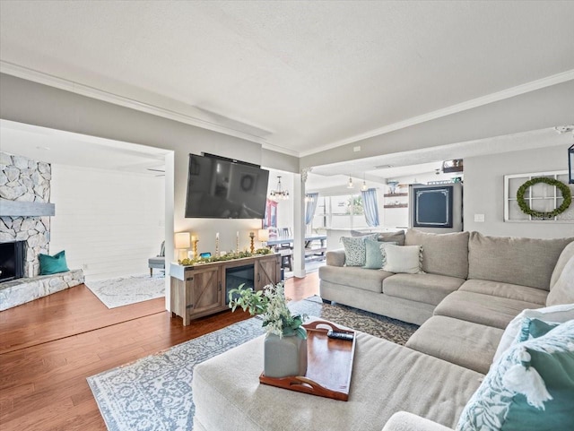 living room featuring hardwood / wood-style flooring, a fireplace, ornamental molding, and a textured ceiling