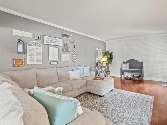 living room featuring wood-type flooring, ornamental molding, and brick wall