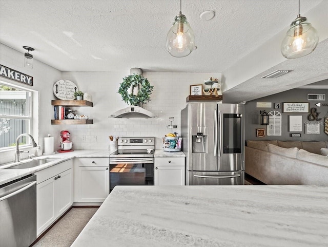 kitchen with pendant lighting, sink, appliances with stainless steel finishes, white cabinets, and decorative backsplash