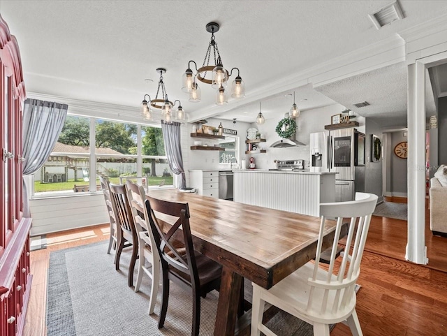 dining space with wood-type flooring, a notable chandelier, and a textured ceiling