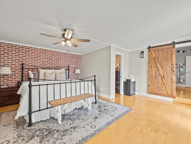 bedroom featuring brick wall, crown molding, a barn door, and hardwood / wood-style floors