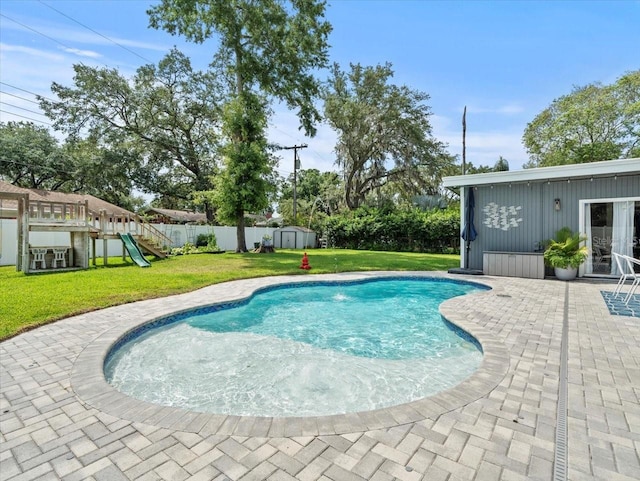 view of pool featuring a playground, a yard, a patio area, and a storage unit