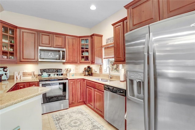 kitchen featuring appliances with stainless steel finishes, sink, light tile patterned floors, and light stone counters