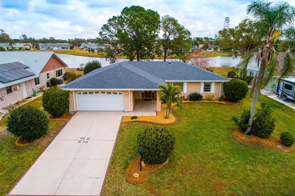 ranch-style house with a garage, a water view, and a front lawn