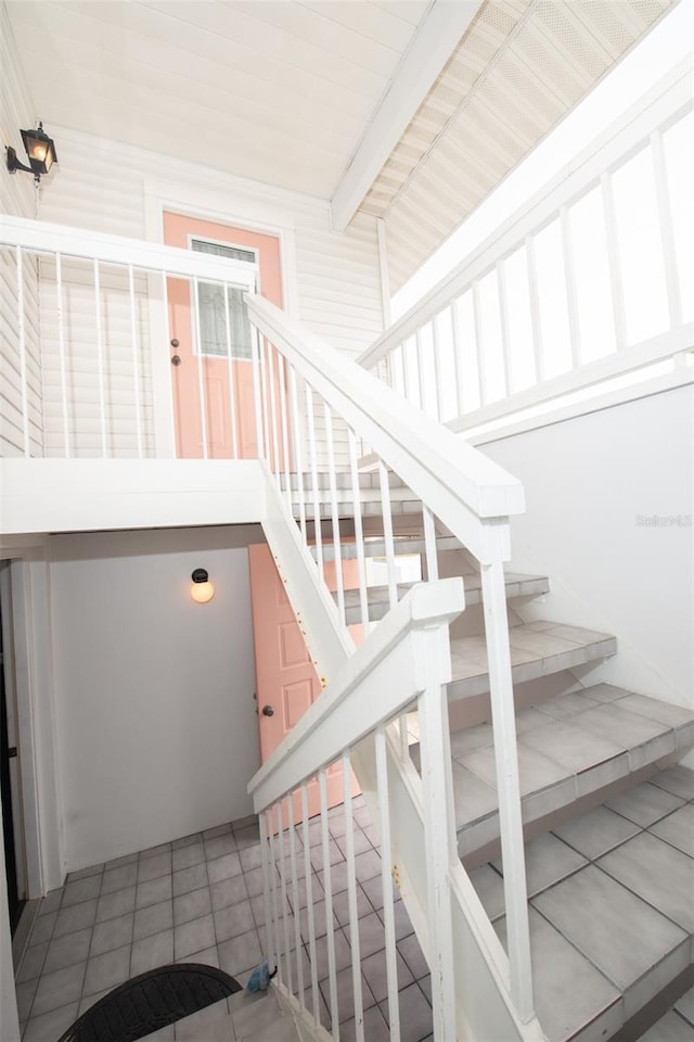 stairway featuring tile patterned flooring and beam ceiling