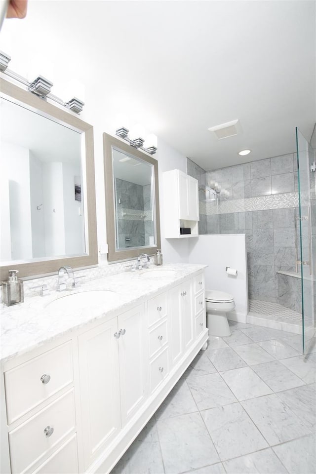 bathroom with vanity, a tile shower, and toilet