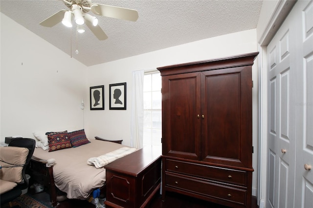 bedroom with ceiling fan, vaulted ceiling, and a textured ceiling