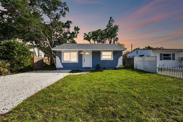 view of front of property featuring a yard, fence, and stucco siding