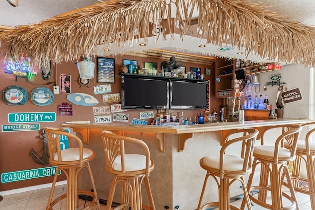 bar featuring light tile patterned floors and a textured ceiling