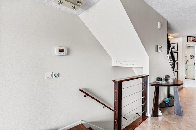 staircase with lofted ceiling and a textured ceiling