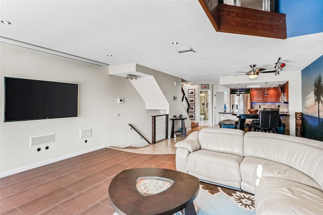 living room featuring ceiling fan, light hardwood / wood-style floors, and a textured ceiling