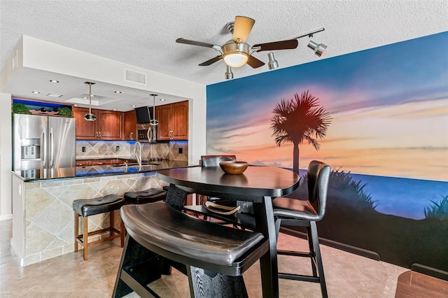 tiled dining area featuring sink, a textured ceiling, and ceiling fan