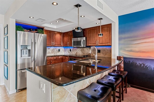 kitchen featuring stainless steel appliances, pendant lighting, a kitchen bar, and kitchen peninsula