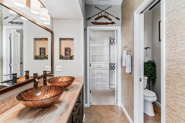 bathroom with tile patterned flooring, vanity, a textured ceiling, and toilet