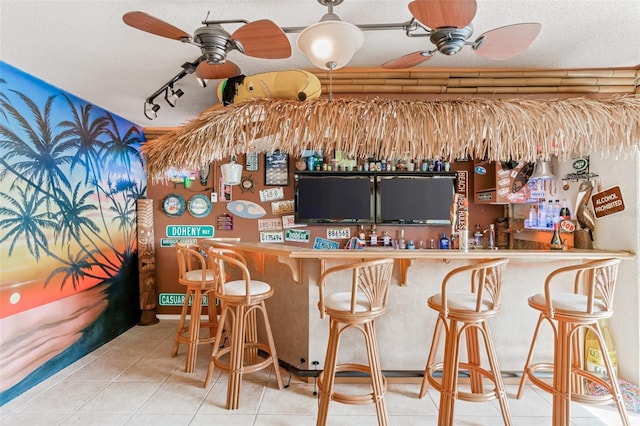 bar with tile patterned flooring, track lighting, a textured ceiling, and ceiling fan