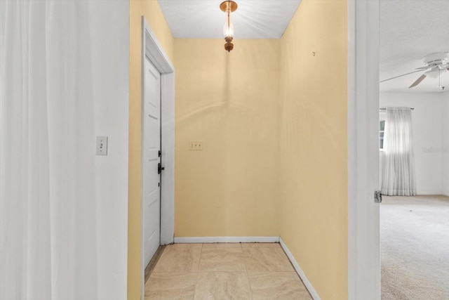 hall with light colored carpet and a textured ceiling