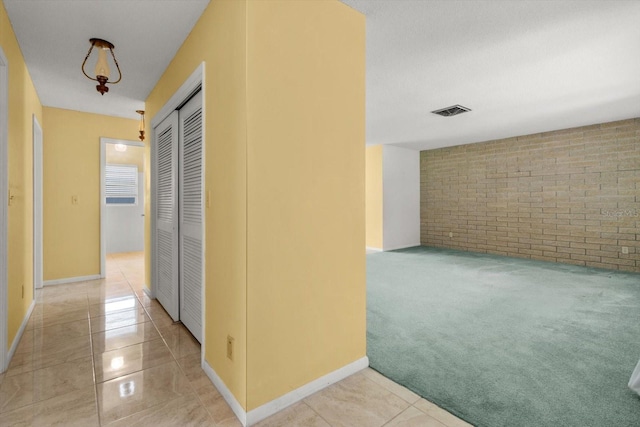 corridor with brick wall and light colored carpet