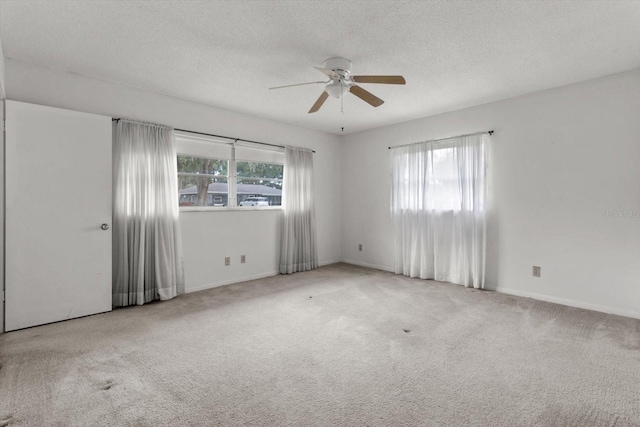 empty room with ceiling fan, light carpet, and a textured ceiling