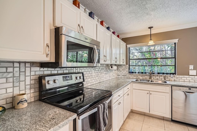 kitchen with light tile patterned flooring, appliances with stainless steel finishes, decorative light fixtures, white cabinetry, and sink