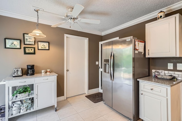 kitchen with pendant lighting, white cabinetry, stainless steel fridge, light tile patterned floors, and a textured ceiling