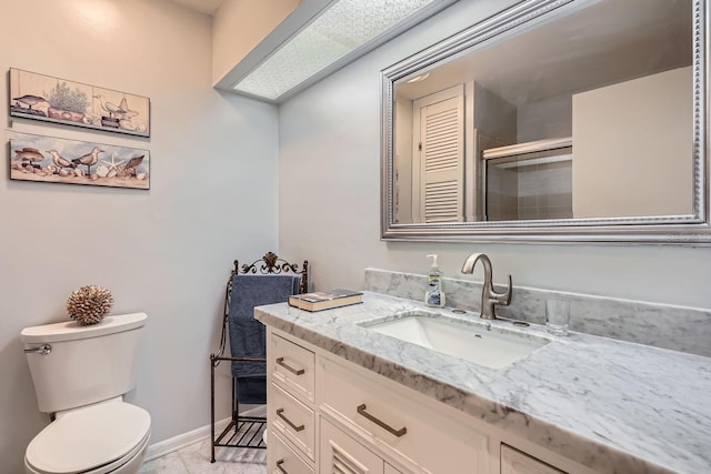 bathroom featuring vanity, a shower with shower door, and toilet