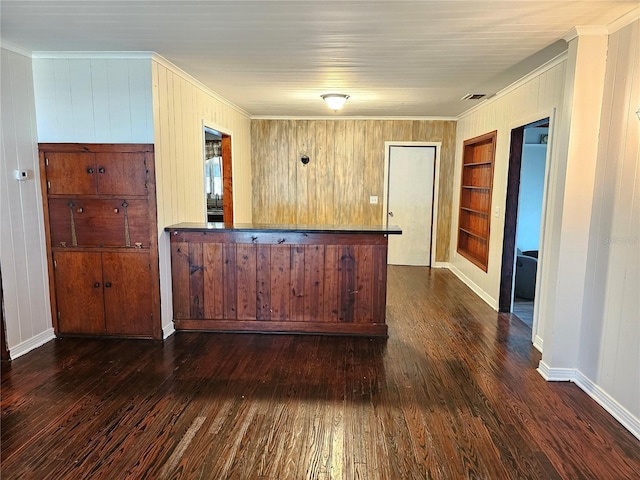 bar featuring dark wood-type flooring, ornamental molding, and built in features