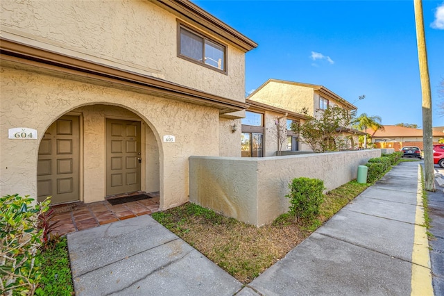 entrance to property featuring fence and stucco siding