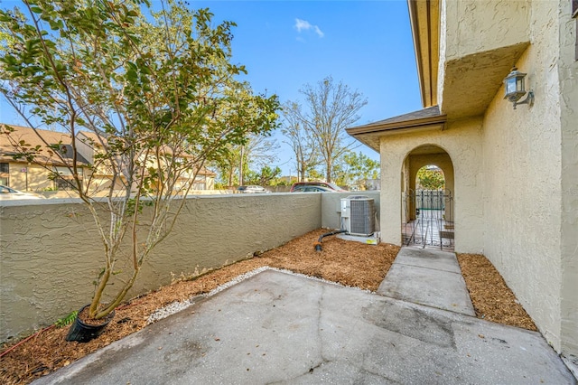 view of yard with central air condition unit, fence private yard, a gate, and a patio