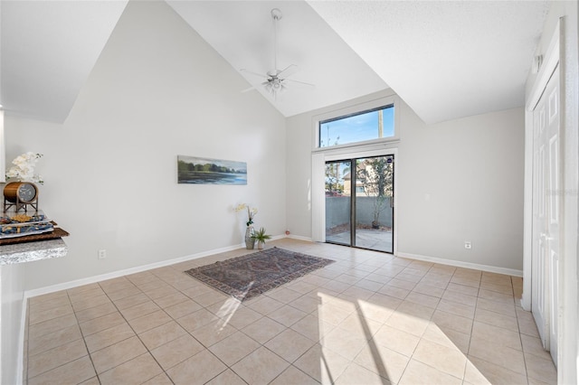 unfurnished room featuring light tile patterned floors, baseboards, high vaulted ceiling, and a ceiling fan