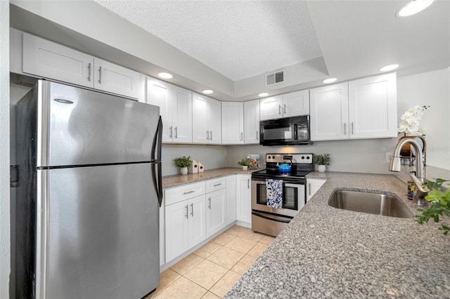 kitchen featuring stainless steel appliances, white cabinetry, a sink, and visible vents