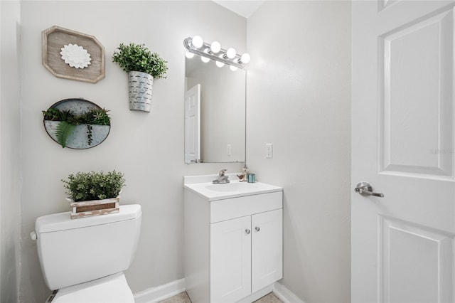 bathroom with baseboards, vanity, and toilet