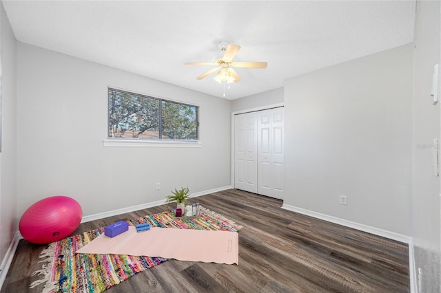 exercise area featuring ceiling fan, baseboards, and dark wood finished floors