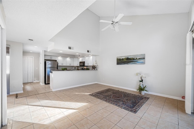 unfurnished living room featuring ceiling fan, light tile patterned flooring, and baseboards