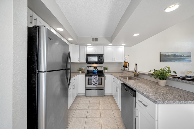 kitchen featuring light tile patterned floors, stainless steel appliances, a sink, visible vents, and white cabinets