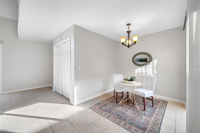 dining space with a chandelier, light tile patterned floors, a textured ceiling, and baseboards