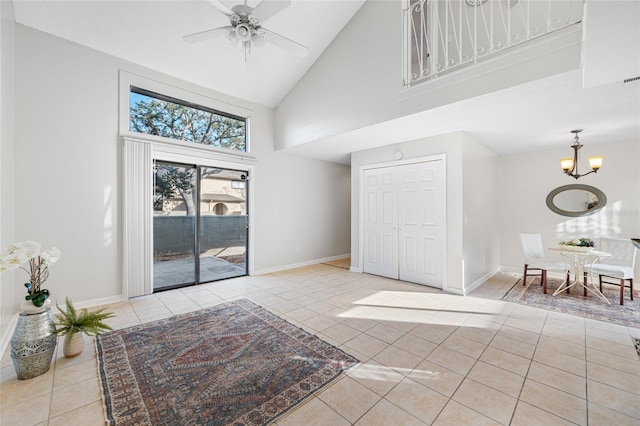 interior space with high vaulted ceiling, ceiling fan with notable chandelier, baseboards, and light tile patterned floors