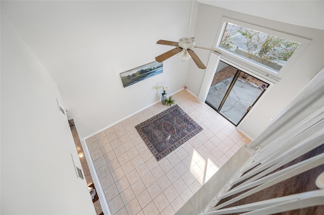 living area featuring a high ceiling, a ceiling fan, visible vents, and baseboards