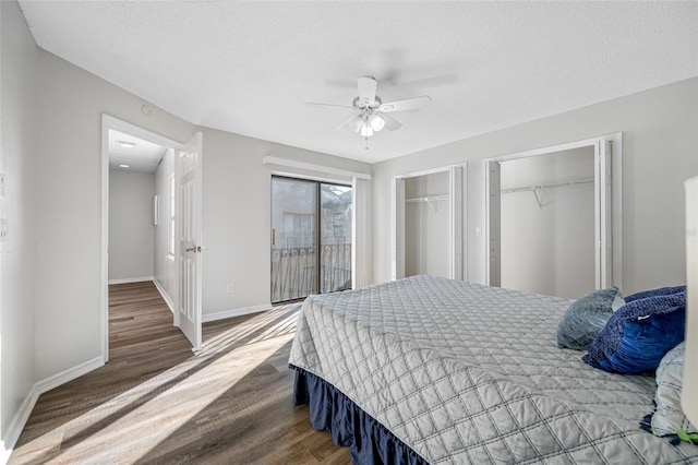 bedroom with a textured ceiling, wood finished floors, baseboards, multiple closets, and access to outside