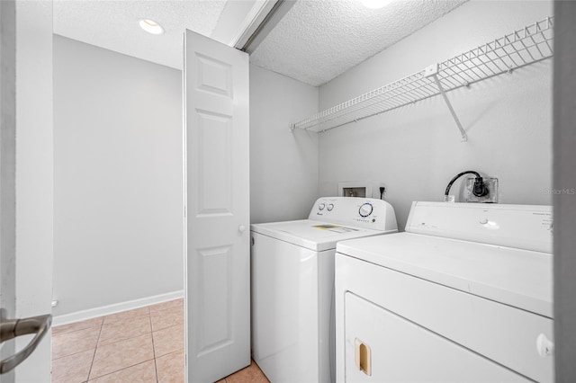 laundry room featuring laundry area, baseboards, a textured ceiling, washer and dryer, and light tile patterned flooring