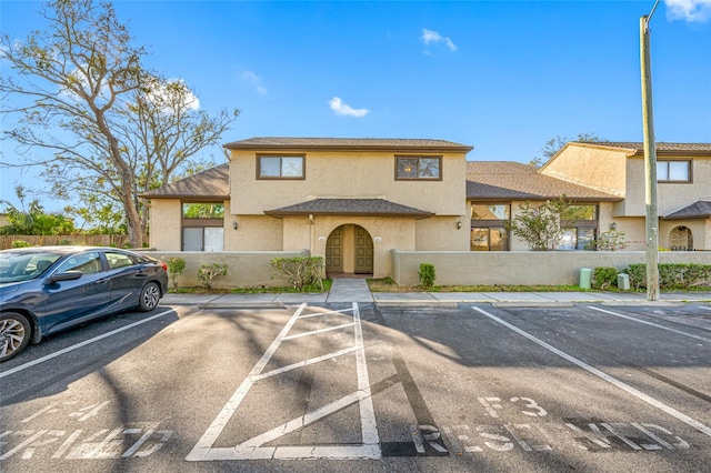 view of front facade featuring uncovered parking, a fenced front yard, and stucco siding