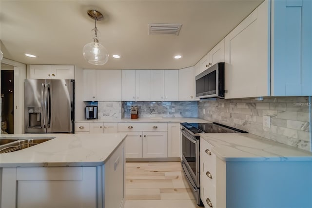 kitchen featuring white cabinetry, backsplash, stainless steel appliances, light stone countertops, and decorative light fixtures