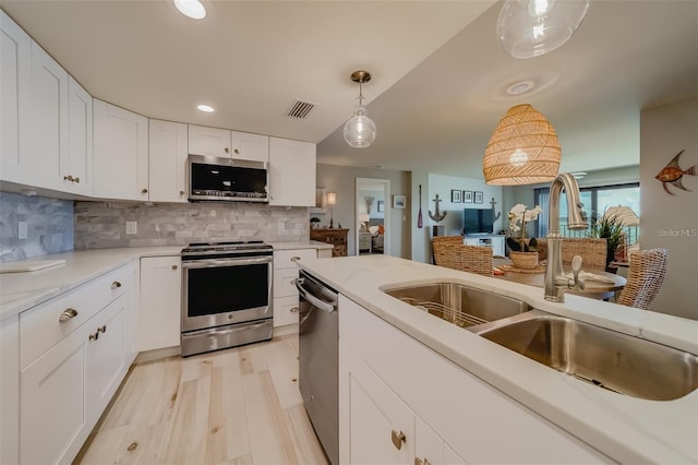 kitchen featuring pendant lighting, sink, appliances with stainless steel finishes, white cabinetry, and tasteful backsplash