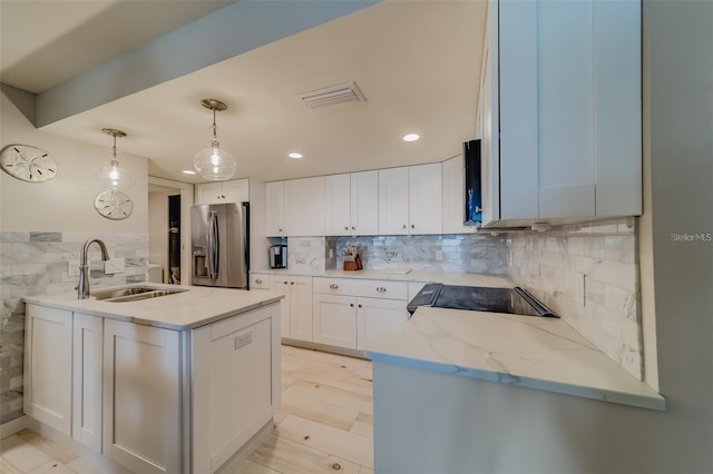 kitchen with decorative light fixtures, white cabinetry, sink, stainless steel fridge with ice dispenser, and light stone countertops