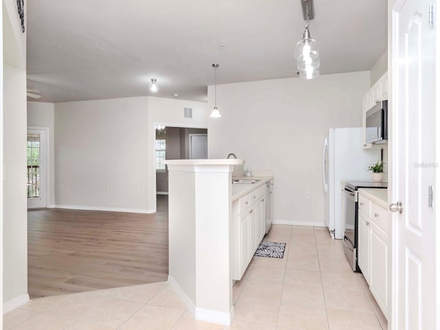 kitchen with light tile patterned floors, white cabinetry, stainless steel appliances, decorative light fixtures, and kitchen peninsula