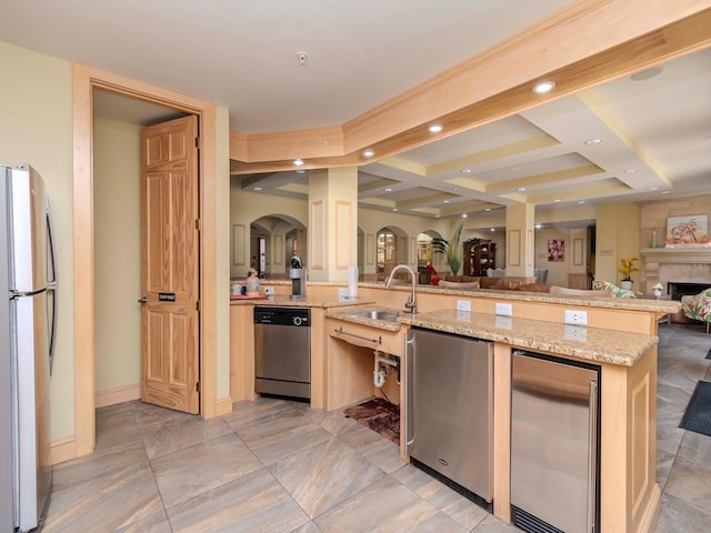 kitchen with sink, a center island with sink, light stone countertops, and appliances with stainless steel finishes