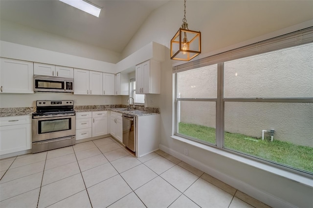 kitchen with lofted ceiling, light tile patterned floors, appliances with stainless steel finishes, white cabinetry, and decorative light fixtures