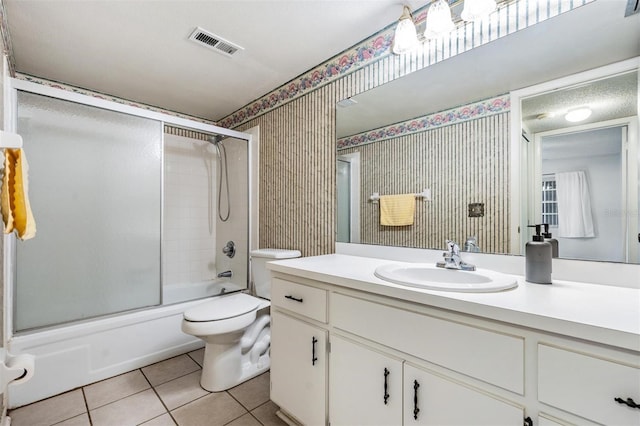 full bathroom with tile patterned flooring, vanity, bath / shower combo with glass door, and toilet