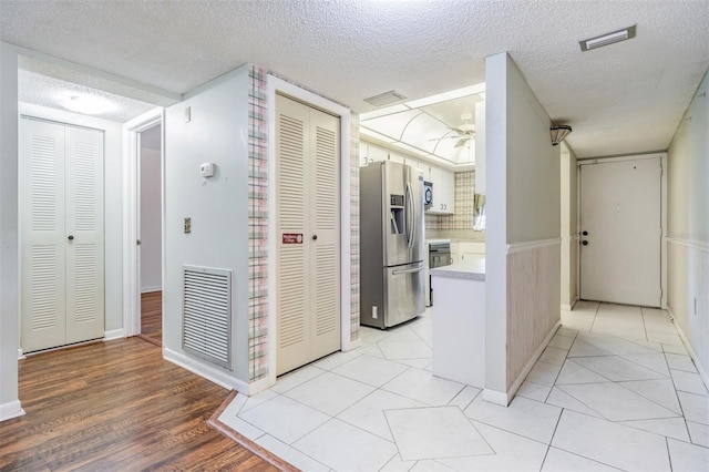 corridor featuring a textured ceiling and light wood-type flooring