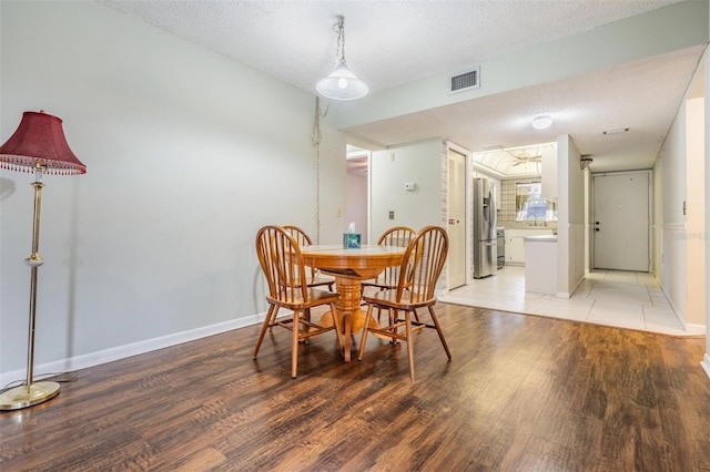 dining room with a textured ceiling and light wood-type flooring