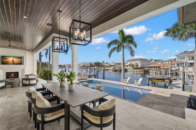 view of patio / terrace featuring ceiling fan, a water view, and exterior fireplace